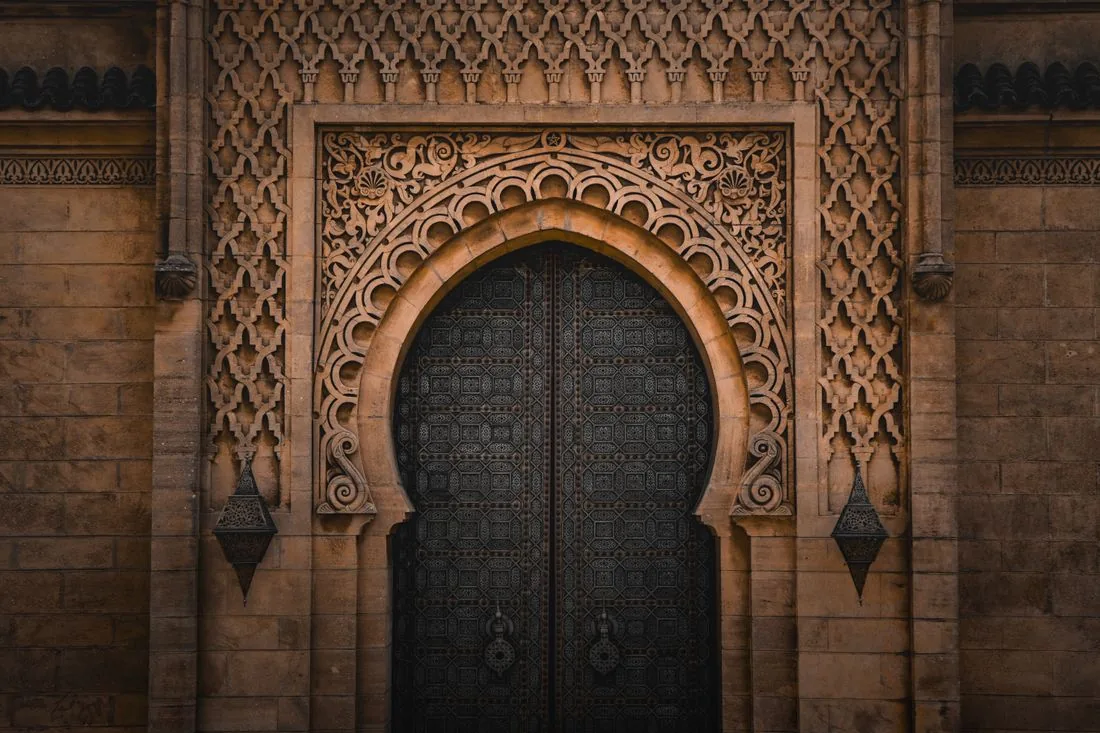 Une porte monumentale sculptée, entre deux lanternes
