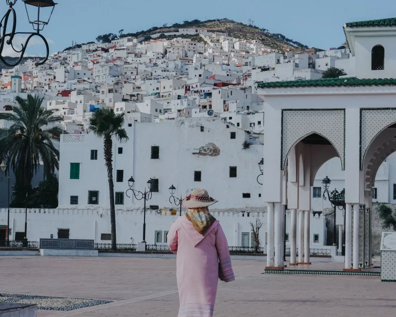 Une jeune femme traverse la place du Palais royal à Tétouan, la médina blanche sur la colline derrière elle